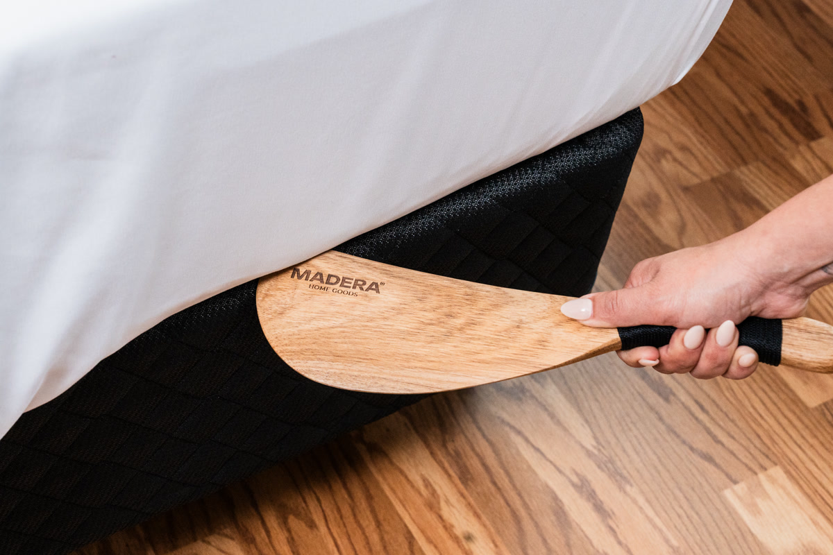 A hand tilting the tucker's handle to raise the mattress edge